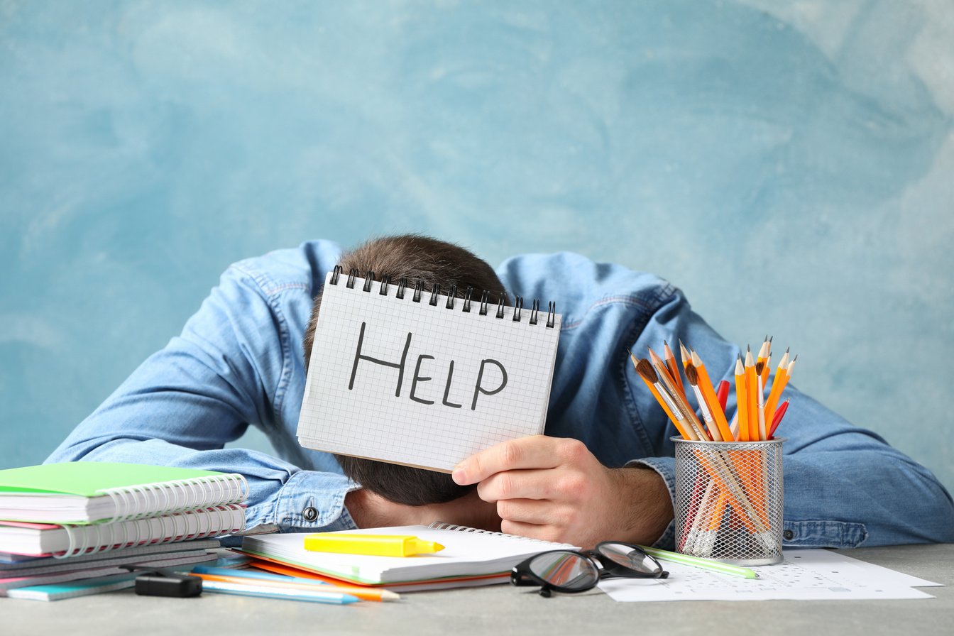 Tired Man Holding a Notebook with Help Written